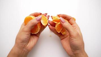 Hands clean tangerine with slices. Peeling process of mandarin on white background video