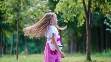 Girl playing on the lawn. Little girl dancing and having fun at the park video