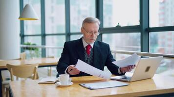 Serious senior businessman in cafe. Businessman working on business project in city cafe video