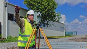 Construction engineer supervising work at building site. Professional engineer surveyor takes measures with theodolite video