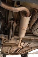 Underside view of car lifted on hydraulic lift in auto repair shop for maintenance and inspection. Vehicle in garage setting ready for service. photo