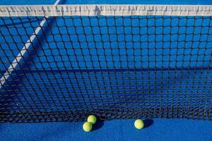 detailed close-up of paddle tennis balls resting at the net on court photo