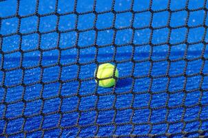 Selective focus, isolated ball on a paddle court, with the net out of focus in the foreground. photo