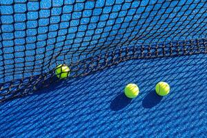 multiple paddle tennis balls lying close to the net on the court photo