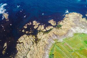 rocky shore of a rocky coast and agricultural fields, aerial view with drone, background for coastal concept photo