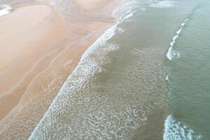 waves arriving at the shore of a beach at low tide, aerial photo with a drone. summer background