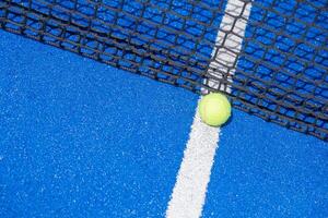 a ball at the foot of the net of a paddle tennis court with the background out of focus, a racket sport background concept photo