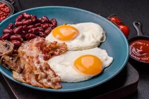 English breakfast with fried eggs, bacon, beans, tomatoes, spices and herbs photo