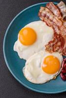 English breakfast with fried eggs, bacon, beans, tomatoes, spices and herbs photo