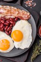 English breakfast with fried eggs, bacon, beans, tomatoes, spices and herbs photo
