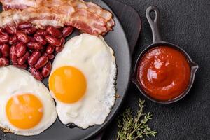 English breakfast with fried eggs, bacon, beans, tomatoes, spices and herbs photo