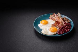 English breakfast with fried eggs, bacon, beans, tomatoes, spices and herbs photo