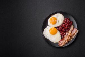 English breakfast with fried eggs, bacon, beans, tomatoes, spices and herbs photo