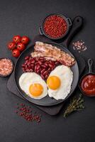 English breakfast with fried eggs, bacon, beans, tomatoes, spices and herbs photo