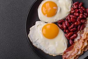 English breakfast with fried eggs, bacon, beans, tomatoes, spices and herbs photo