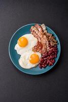 English breakfast with fried eggs, bacon, beans, tomatoes, spices and herbs photo