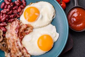 English breakfast with fried eggs, bacon, beans, tomatoes, spices and herbs photo