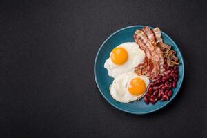 English breakfast with fried eggs, bacon, beans, tomatoes, spices and herbs photo