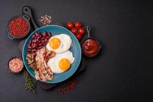 English breakfast with fried eggs, bacon, beans, tomatoes, spices and herbs photo