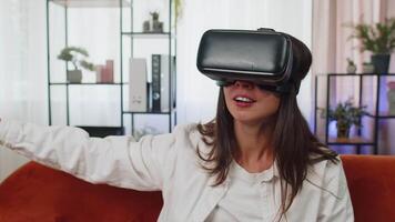Young girl use virtual reality headset glasses at home play 3D game making gestures with hands video