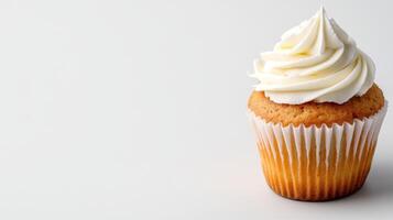 Freshly baked vanilla cupcake topped with creamy frosting photo