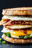 Savory breakfast sandwich stacked high with bacon and eggs photo