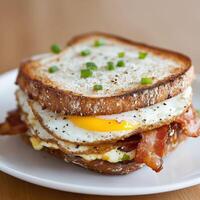 Delicious breakfast sandwich stacked with bacon, eggs, and green onions photo