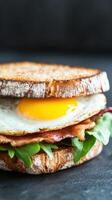 Delicious breakfast sandwich with egg, bacon, and greens on toasted bread photo