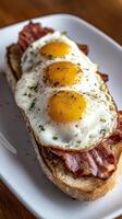 Breakfast toast with fried eggs and crispy bacon served on a white plate photo