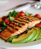 Freshly grilled salmon served with vegetables and avocado photo