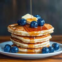 Stack of pancakes topped with blueberries and syrup photo