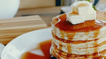 Syrupy pancakes stacked high with butter on a white plate photo
