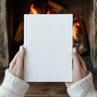 Cozy setting with a blank book held by hands near a fire photo