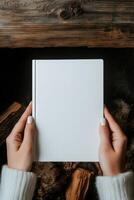 Hands holding a blank notebook above wooden logs photo