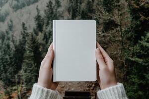 Hands hold a blank notebook in a forest setting photo