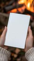 Hands holding a white notebook near a warm fire photo