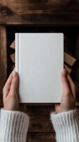 Hands holding a blank white notebook near a cozy fireplace photo