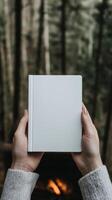 Hands holding a blank notebook in a forest setting photo