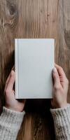 Hands holding a blank diary on a wooden table surface photo