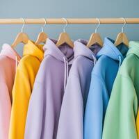 Assorted pastel hoodies hanging on a rack in bright colors photo