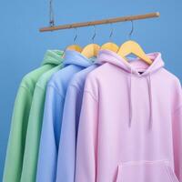 Colorful hoodies displayed on hangers against blue background photo