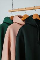 Hoodies hanging on a wooden rack in a minimalistic setting photo