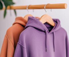 Two stylish hoodies displayed on a wooden hanger photo