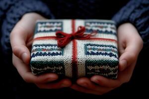 Gift wrapped in knitted pattern held by hands photo