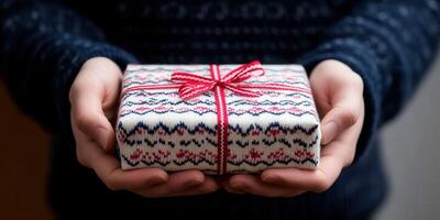 Gift wrapped in festive design held by person indoors photo