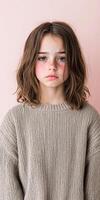 Young girl with tousled hair posing against a pink background photo