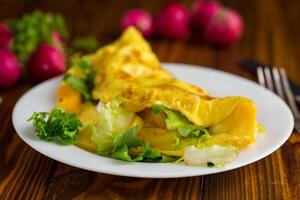 egg roll with sweet pepper and salad, on a wooden table photo