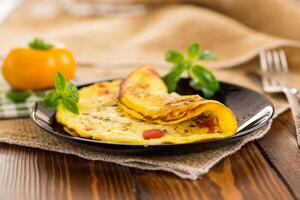 fried omelette with sweet pepper and vegetables in a plate on a wooden table photo
