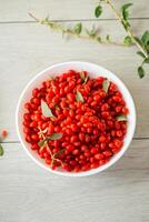 fresh ripe red goji berries in a bowl on a wooden table photo