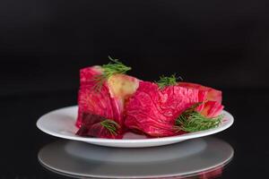 pickled cabbage with beets and carrots, in a plate, isolated on black background photo